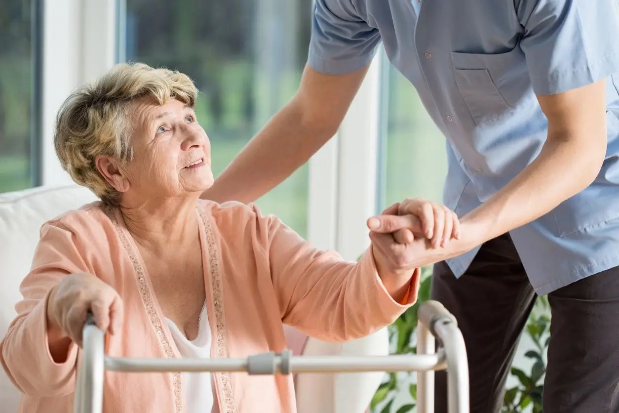 Gina's Care LLC A woman in a pink shirt holding the hand of another person.