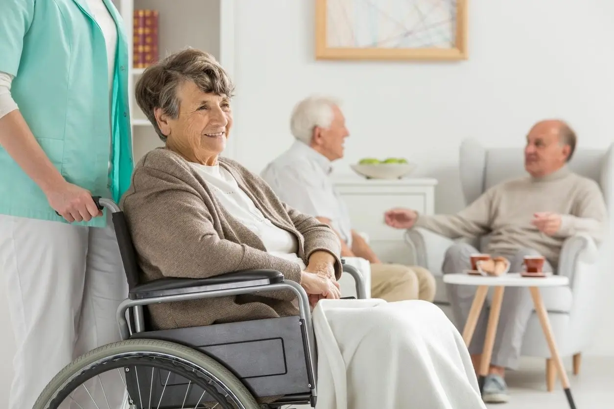 Gina's Care LLC A woman in a wheelchair with two other people sitting on the couch.